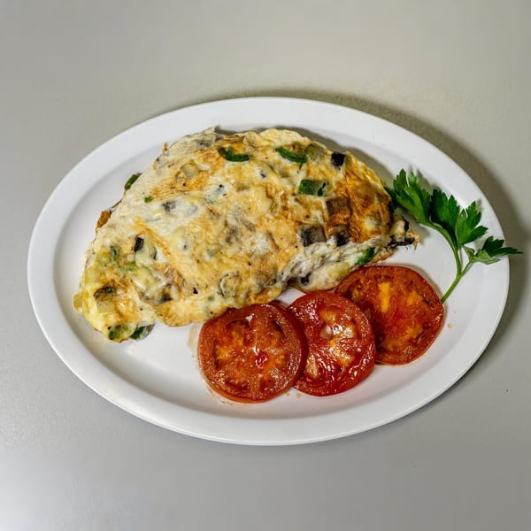 Cherry Pit Cafe's omelet with vegetables and cheese, served with three grilled tomato slices and parsley.